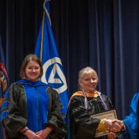 Provost Mili shakes hands and takes picture with 2 women